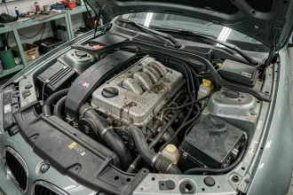 Moteur BMW M47 diesel quatre cylindres visible dans le compartiment moteur d'une BMW 320d en atelier mécanique